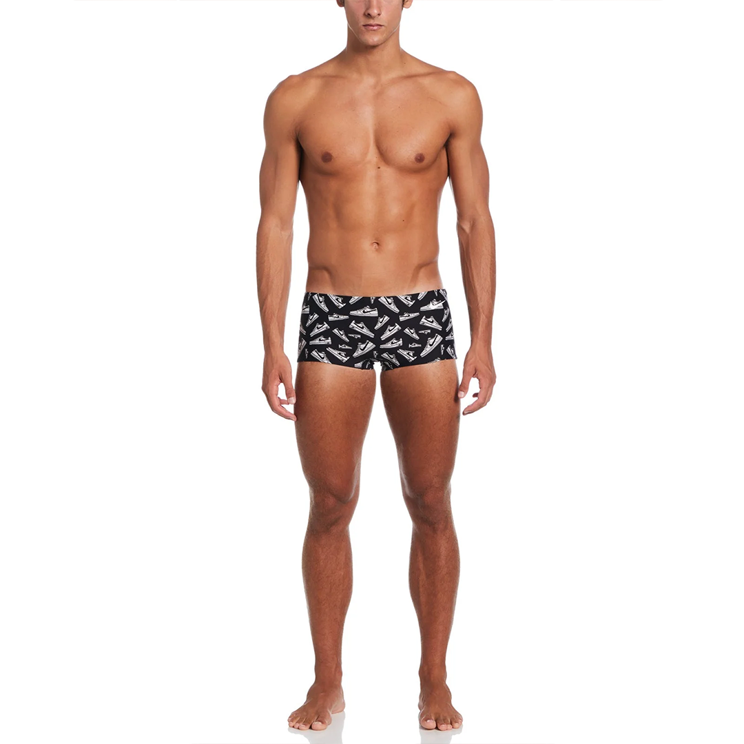 Man wearing black swim trunks with white pattern on a white background