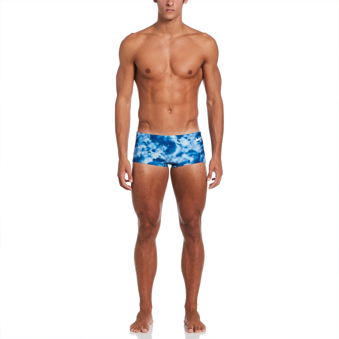 Man wearing blue tie-dye swim trunks on a white background
